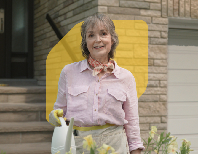 A woman that is 55+ stand in front of her home.